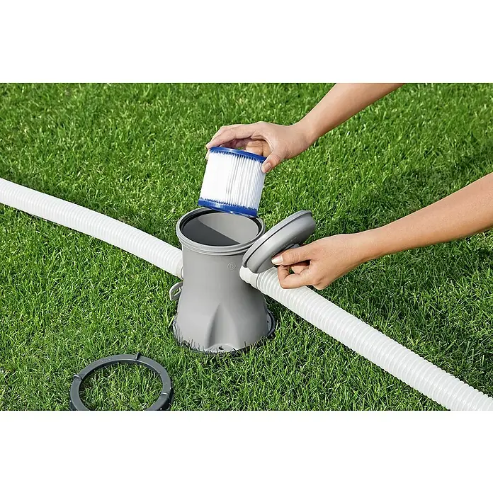 Bestway Filterkartusche - Filterleistung: 1.029 l/h - Der Bestway Flowclear Filter wird in eine graue Filterpumpe auf grünem Gras eingesetzt, angeschlossen an weiße Schläuche.