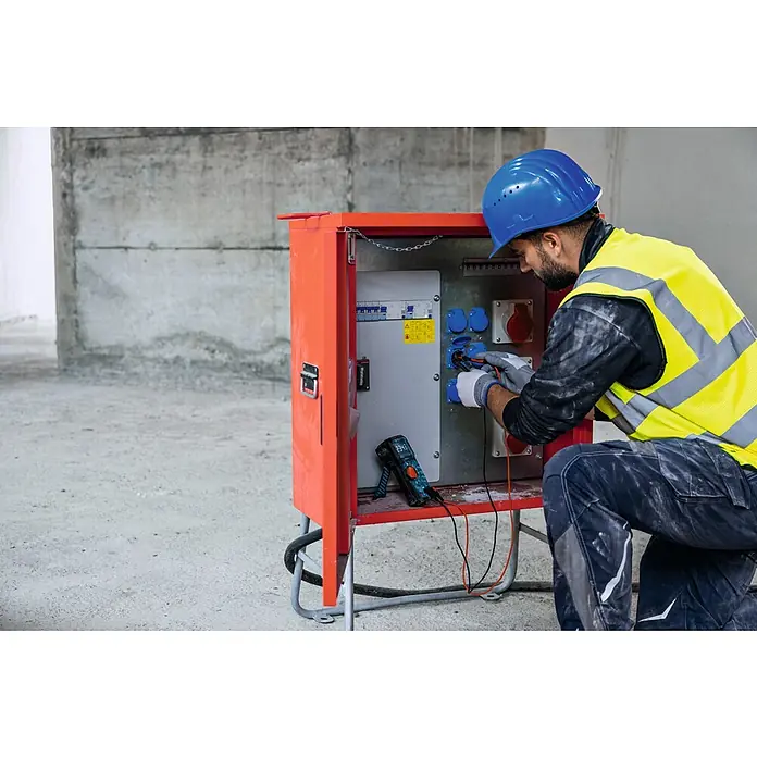 Bosch Professional Digital-Multimeter GDM 600-15 - 600 V, Blau, Schwarz - Ein Bauarbeiter prüft mit einem Multimeter eine orangefarbene Baustromverteilerbox mit blauen und roten Steckdosen. Der Arbeiter trägt Schutzkleidung.