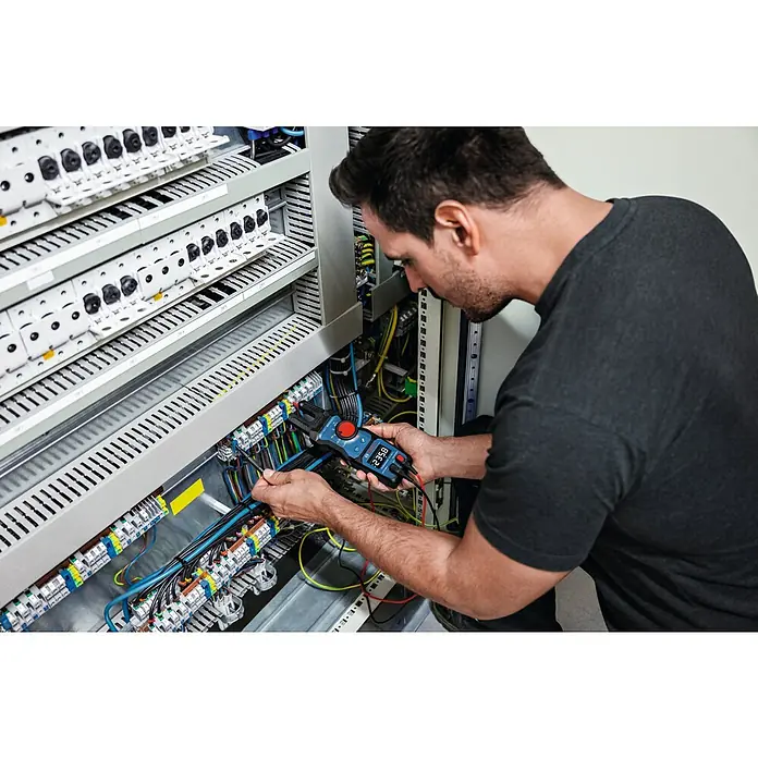 Bosch Professional Stromzange GFM 1000-15 - 1.000 V, Blau, Schwarz - Elektriker prüft die Spannung mit einem digitalen Multimeter an einem elektrischen Panel.