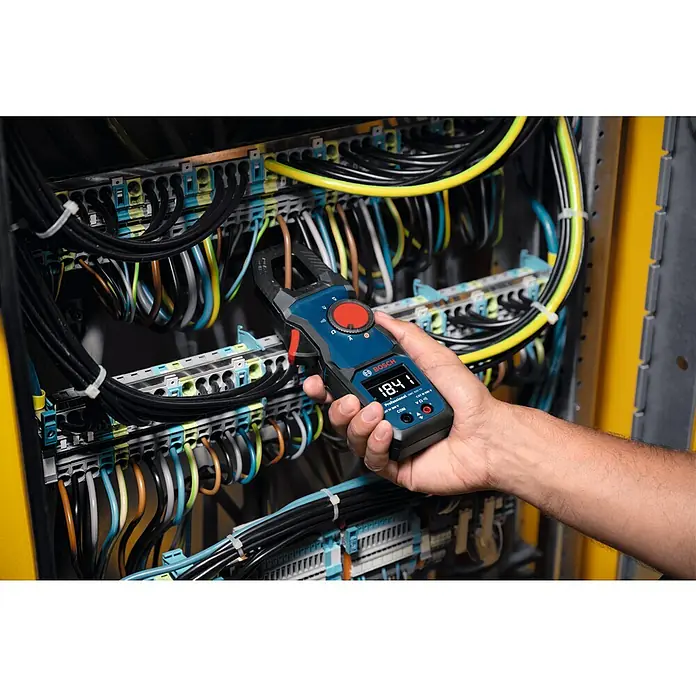 Bosch Professional Stromzange GMC 600-15 - 600 V, Blau, Schwarz - Ein Bosch-Multimeter wird verwendet, um die Stromstärke in einem Schaltschrank mit mehreren Kabeln zu messen. Das Gerät zeigt einen Wert von 18.4 V an.