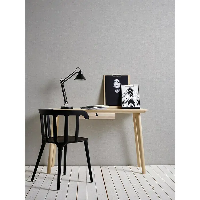 A.S. Création Vliestapete Majestic - Grau, Uni, 10,05 x 0,53 m - Stylischer Arbeitsplatz mit hellem Holzschreibtisch, schwarzem Stuhl und Lampe sowie minimalistischen Dekoelementen für ein modernes Ambiente.