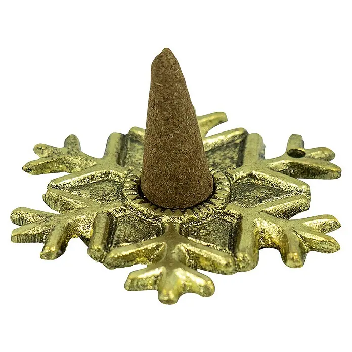 Räucherkerze Wintertraum - 1 Stk., Duft: Sortiert - Ein Nahaufnahme eines goldenen Räucherstäbchenhalters in Form einer Schneeflocke mit einem braunen Räucherkegel darauf, vor einem schwarzen Hintergrund.