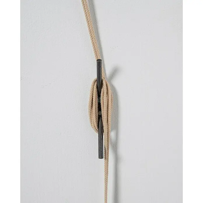 Estor enrollable Yute - An x Al: 120 x 250 cm, Cerezo - Un primer plano de un cordón beige colgado de un pasador de metal oscuro fijado a una pared blanca, que muestra un diseño minimalista.
