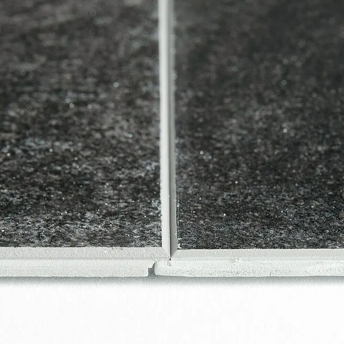 Grosfillex Wall+ Wandpaneel - Black Stone, 600 x 300 x 5 mm - Nahaufnahme von zwei Vinyl-Bodenfliesen mit dunkler, gesprenkelter Oberfläche und hellgrauer Basis, die Stoß an Stoß auf einem weißen Untergrund liegen.