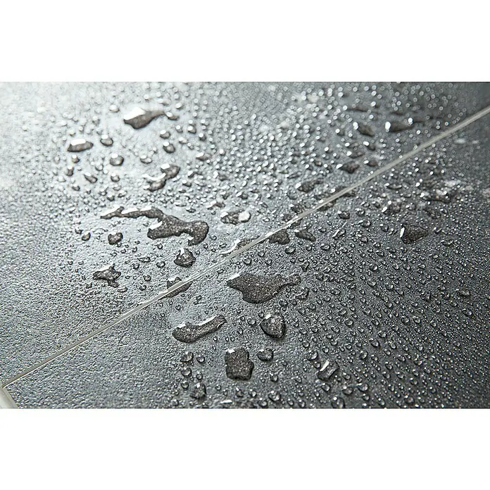 Grosfillex Wall+ Wandpaneel - Black Stone, 600 x 300 x 5 mm - Nahaufnahme von Fliesen mit Wassertropfen. Die dunklen Fliesen weisen eine feine Textur und spiegelnde Oberfläche auf, was das Licht reflektiert.