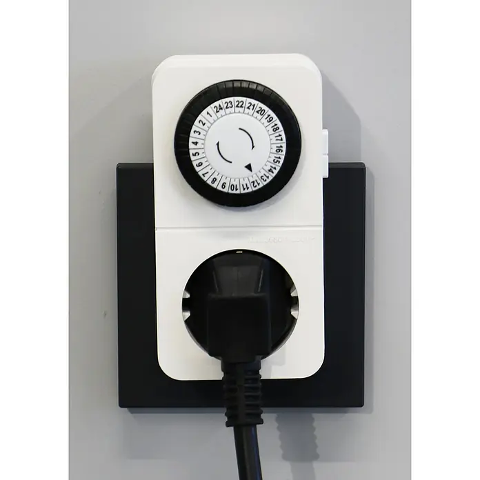 UniTEC Tages-Zeitschaltuhr Greenline Analog - Weiß, 3.680 W - Eine Zeitschaltuhr in Weiß ist an einer schwarzen Wandsteckdose angebracht, in die ein schwarzes Kabel gesteckt ist.