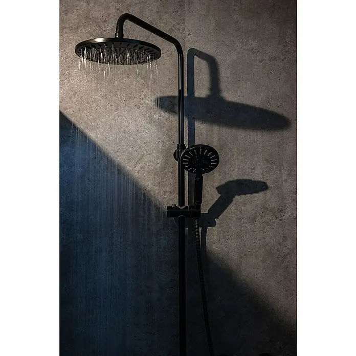 Grosfillex Wall+ Wandpaneel - Grey Concrete, 2.600 x 600 x 5 mm - Eine moderne, schwarze Duscharmatur mit Kopf- und Handbrause vor einer grauen Betonwand, die Eleganz und Funktionalität vereint.