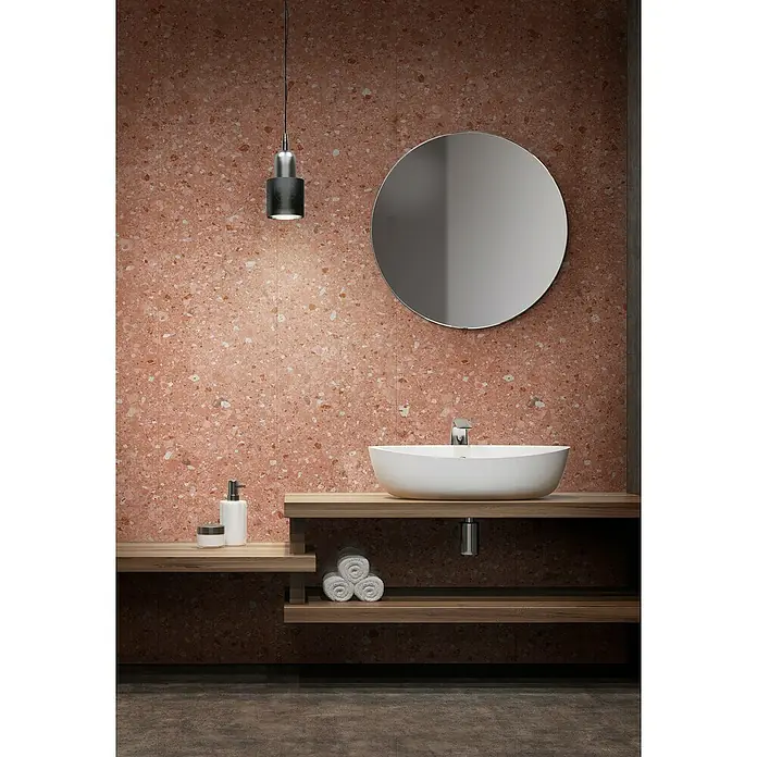 Grosfillex Wandpaneel Element 3D - Terrazzo Rose, 2.600 x 375 x 8 mm - Badezimmer-Interieur mit stilvollem Waschbecken, runden Spiegel und Terrazzo-Wand, beleuchtet von einer modernen Hängeleuchte für eine warme Atmosphäre.