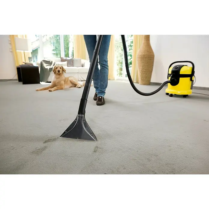 Kärcher Waschsauger SE 4004 - 1.000 W, Behältervolumen: 4 l - Teppichreiniger im Einsatz mit gelbem Nass- und Trockensauger zur Fleckenentfernung auf Teppichböden. Ein Hund liegt im Hintergrund.