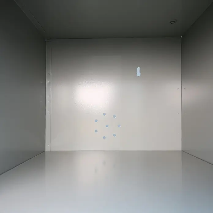 Lüllmann Fächerschrank - H x B x T: 180 x 74 x 50 cm, Lichtgrau/Enzianblau, Fertig montiert, Anzahl Fächer: 16 Stk. - Innenansicht eines leeren, grauen Metallschranks mit Bohrlöchern und einem Haken an der Rückwand. Ideal für Lagerung und Organisation.