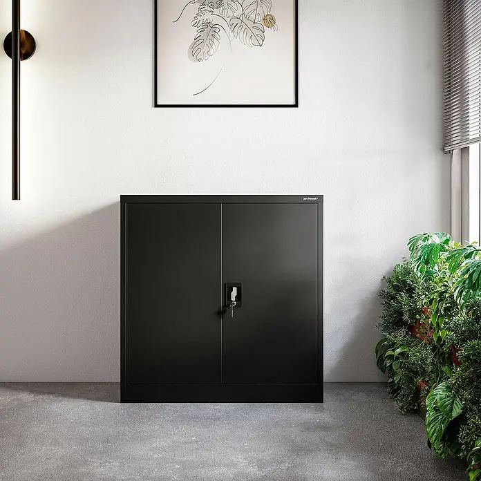 Jan Nowak Aktenschrank Beata - B x T x H: 90 x 40 x 92,5 cm, Schwarz - Schwarzer Jan Nowak Aktenschrank mit zwei Türen und Schloss vor weißer Wand mit Bild und Pflanze.