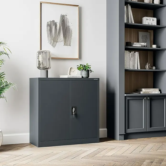 Jan Nowak Aktenschrank Beata - B x T x H: 90 x 40 x 92,5 cm, Anthrazit - Aufnahme eines grauen Büroschranks aus Metall mit zwei Türen und Schloss vor einer Wand mit einem gerahmten Bild und einem Bücherregal.
