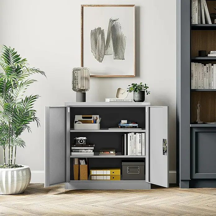 Jan Nowak Aktenschrank Beata - B x T x H: 90 x 40 x 92,5 cm, Grau - Ein grauer Büroschrank mit geöffneten Türen, gefüllt mit Büchern und Ordnern, unter einem modernen Gemälde und einer Lampe.