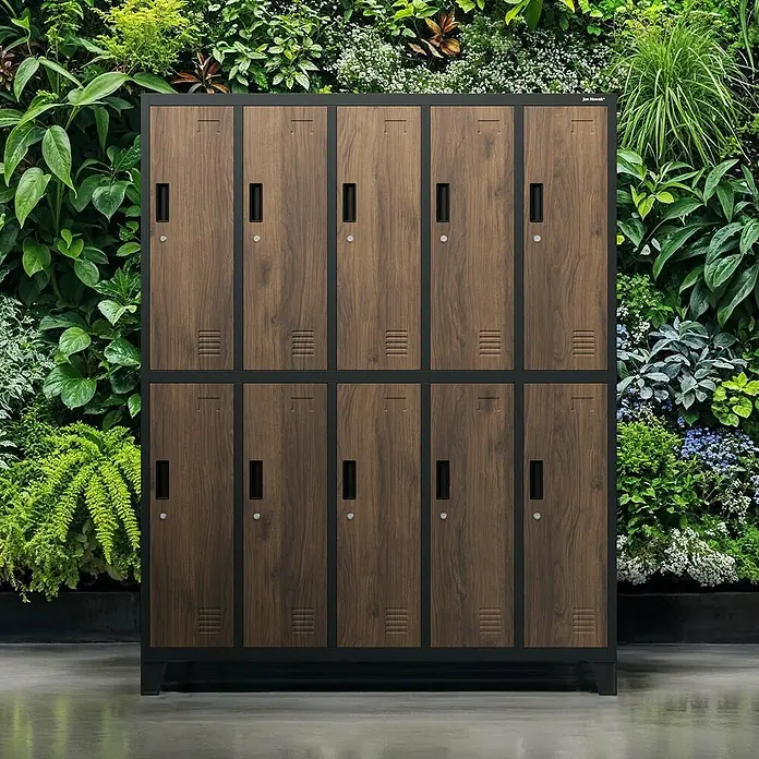 Jan Nowak Spind Bartek - B x T x H: 136 x 45 x 172 cm, Anthrazit/ Nussbaum - Ein Schrank mit Holztüren und schwarzen Rahmen steht vor einem lebendigen grünen Wandgarten.