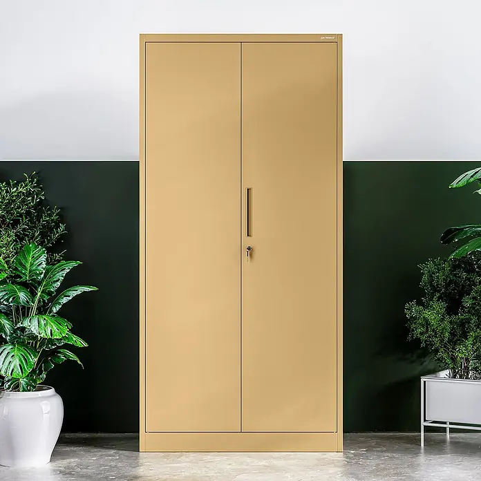 Jan Nowak Metall-Mehrzweckschrank Dawid - H x B x T: 185 x 90 x 45 cm, Beige - Ein goldfarbener Metallschrank mit zwei Türen und einem Griff steht vor einer zweigeteilten Wand.