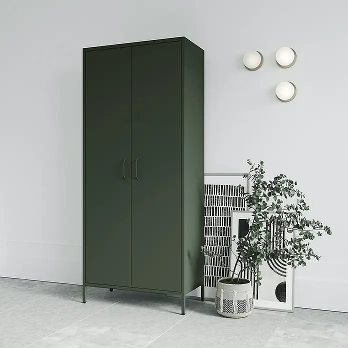 Jan Nowak Kleiderschrank Flavio - H x B x T: 185 x 80 x 45 cm, Flaschengrün - Eine Aufnahme eines modernen, dunkelgrünen Metallkleiderschranks vor einer weißen Wand mit Deko-Elementen.
