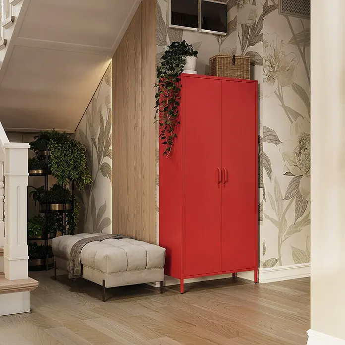 Jan Nowak Kleiderschrank Flavio - H x B x T: 185 x 80 x 45 cm, Rot - Eine stilvolle Aufnahme zeigt einen roten Schrank, der mit Pflanzen und einem Weidenkorb dekoriert ist, neben einem grauen Hocker im Flur.