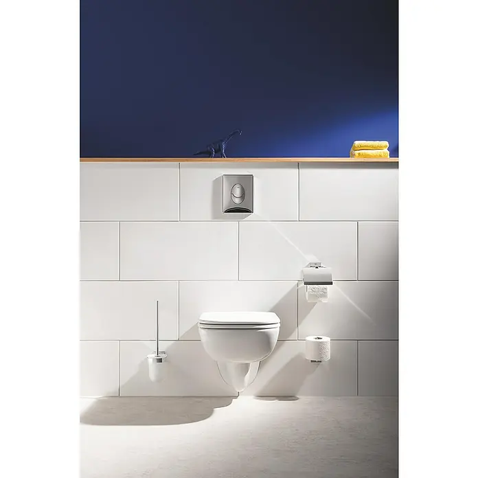 Grohe QuickFix Start Cube WC-Bürstengarnitur - Metall - Modernes Badezimmer mit hängendem WC, weißer Fliesenwand und Holzregal mit Dekorationen für ein stilvolles Ambiente.