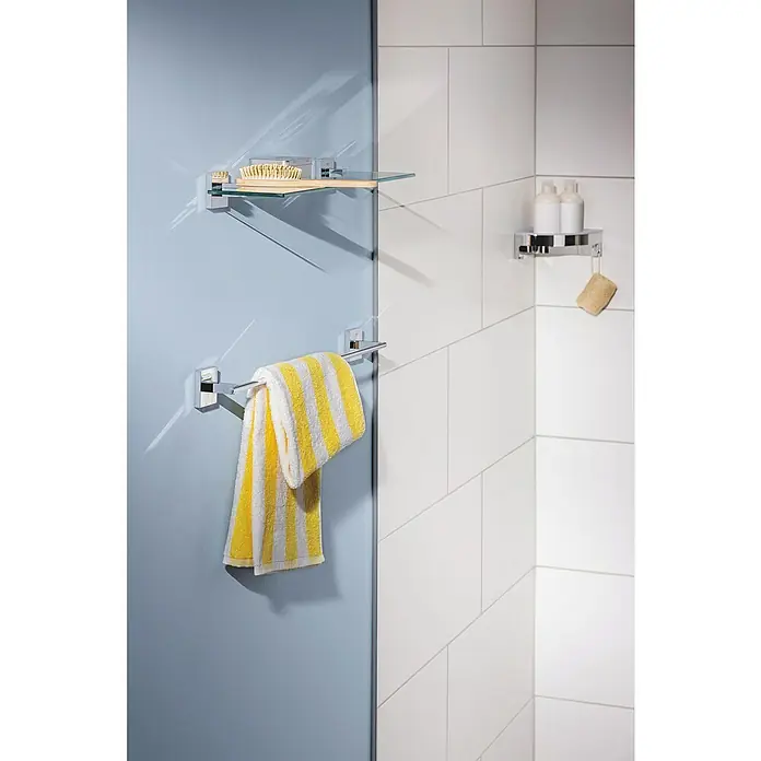 Grohe QuickFix Start Cube Badetuchhalter - Breite: 61,2 cm, Glänzend - Eine Handtuchstange mit einem gelb-weiß gestreiften Handtuch, ein Glasregal mit Badutensilien und ein Regal mit Lotionen im Badezimmer.