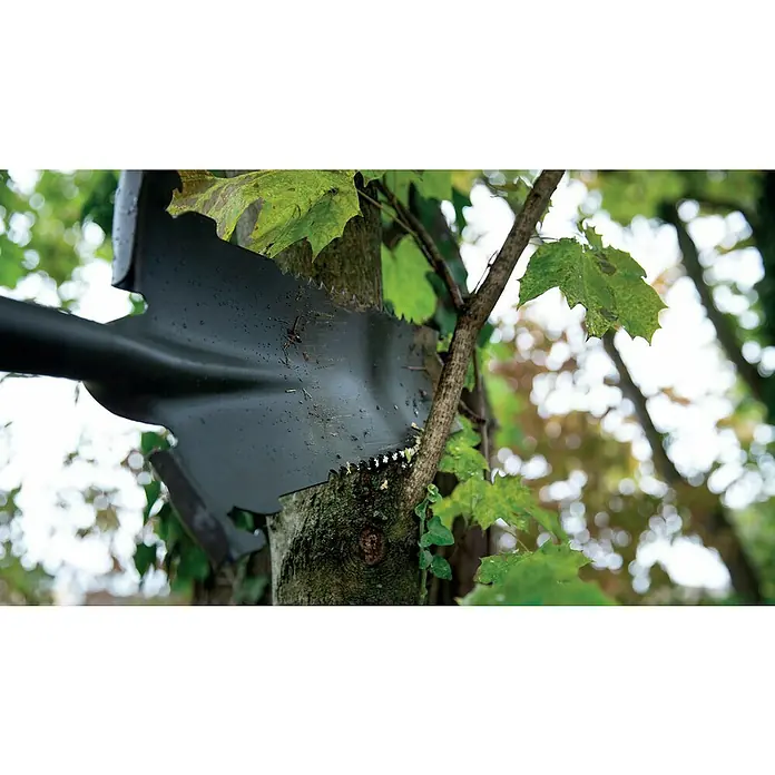BAUHAUS Rodespaten - Arbeitsbreite: 34,5 cm, Länge: 114 cm - Nahaufnahme eines schwarzen Spatens mit Sägezähnen, der in einem Baum steckt, umgeben von grünen Blättern.