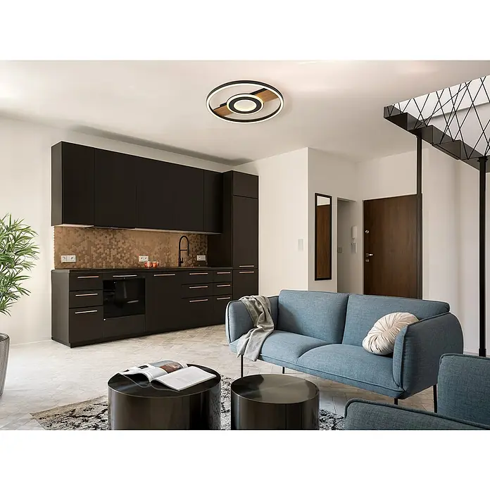 Globo Plafón LED Blacky - Marrón, 24 W, Blanco cálido - Interior de apartamento moderno con cocina marrón oscuro, sofá azul y lámpara de techo redonda que crean un ambiente elegante.