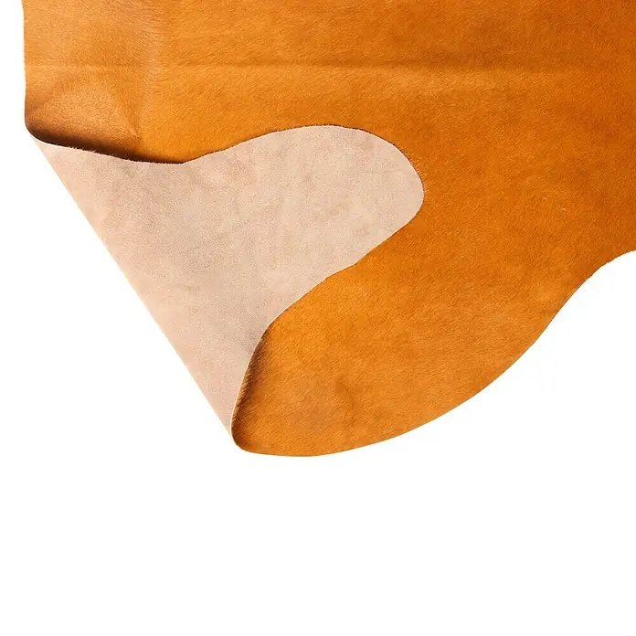 Esbeco Kuhfell - Gelb, 100 % Echtfell - Nahaufnahme einer goldbraunen Lederhaut, teilweise umgeschlagen, um die helle Innenseite zu zeigen. Ideal für hochwertige Handwerkskunst und Design.