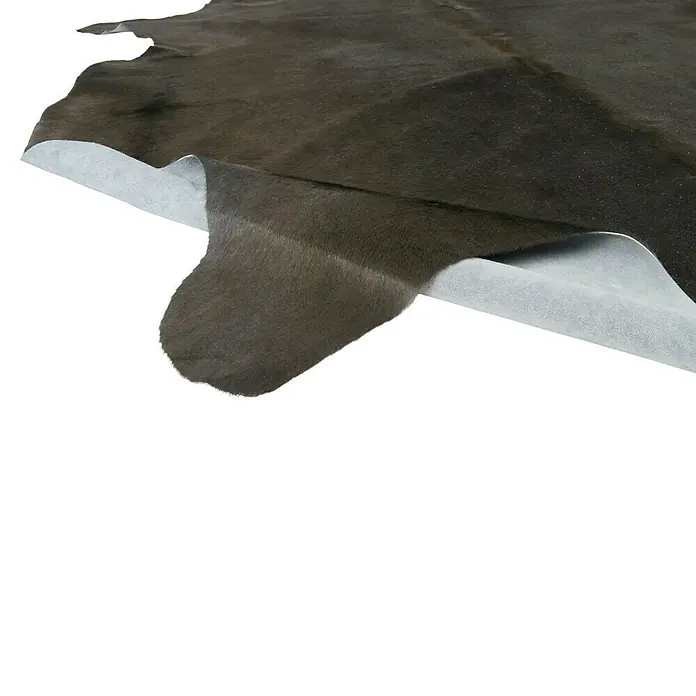 Esbeco Kuhfell - Dunkelgrau, 100 % Echtfell - Nahaufnahme eines braunen Kuhfells mit weißer Unterseite, das eine luxuriöse Textur und organische Form zeigt.