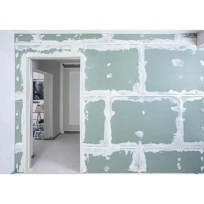 Knauf Pocket Kit Easy Schiebetürsystem Standard - Stahl, Für CW 75 mm - Innenaufnahme eines Zimmers im Rohbau mit Trockenbauwänden, die verspachtelt werden und einen unfertigen, aber fortschreitenden Bauprozess zeigen.