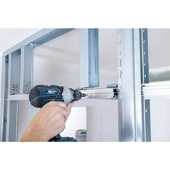 Knauf Pocket Kit Easy Schiebetürsystem Standard - Stahl, Für CW 75 mm - Nahaufnahme eines Handwerkers, der mit einem Akkubohrer eine Metallschiene befestigt. Das Werkzeug ist auf die Installation fokussiert.
