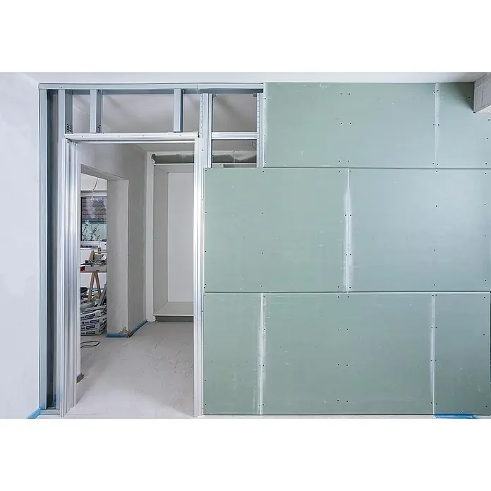 Knauf Pocket Kit Easy Schiebetürsystem Standard - Stahl, Für CW 75 mm - Innenaufnahme eines Hauses im Bau mit einer Wand aus Gipskartonplatten und Metallrahmen, die eine Türöffnung umgibt.