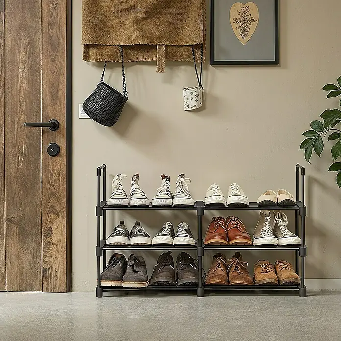 Schuhregal - L x B x H: 30 x 45 x 106 cm, Schwarz - Schuhregal aus Metall mit drei Ebenen, gefüllt mit verschiedenen Schuhen in einem Flur neben einer Holztür.