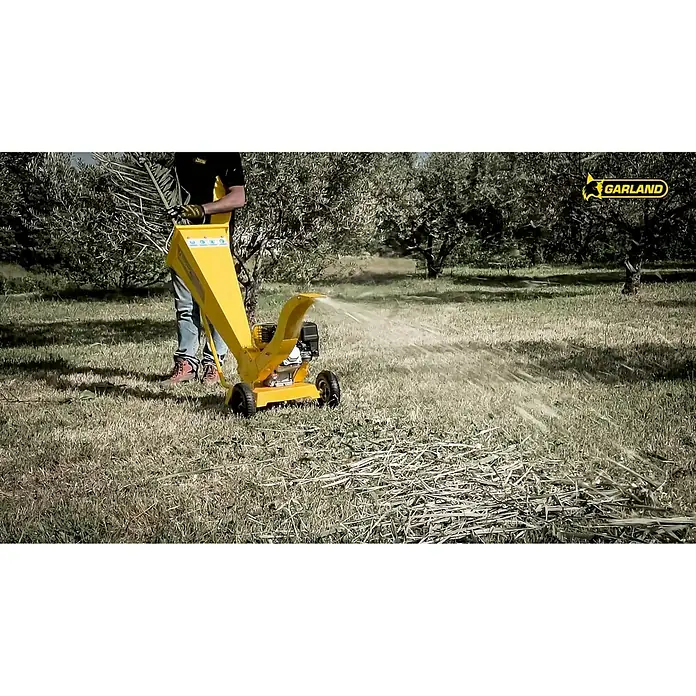 Garland Biotrituradora de gasolina 780 QG-V17 - Grosor de rama máx.: 6 cm, 4,3 kW, Cilindrada: 212 cm³ - Una biotrituradora amarilla de Garland en acción, triturando ramas y expulsando mulch. Ideal para jardinería.