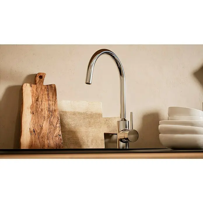 BAUHAUS Küchenzeile Sandra - Breite: 310 cm, Weiß, Farbe Korpus: Artisan Eiche, Mit Elektrogeräten - Elegante Küchenarmatur aus poliertem Chrom neben Holzschneidebrett und Stapel weißer Schalen, die eine stilvolle Küchenszene erzeugen.