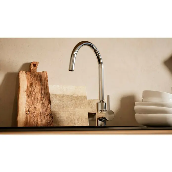 BAUHAUS Küchenzeile Sandra - Breite: 310 cm, Grau, Farbe Korpus: Artisan Eiche, Mit Elektrogeräten - Nahaufnahme einer modernen Chrom-Küchenarmatur vor dem Hintergrund von Schneidebrettern und einer Schüssel mit Tellern.