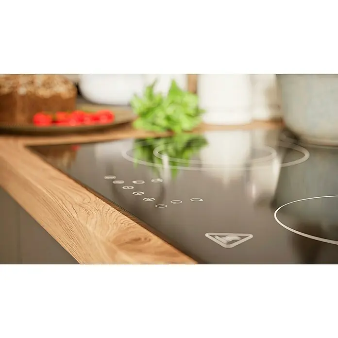 BAUHAUS Küchenzeile Sandra - Breite: 280 cm, Grau, Farbe Korpus: Artisan Eiche, Mit Elektrogeräten - Nahaufnahme eines eleganten, schwarzen Induktionskochfelds mit Touch-Bedienfeld und hölzerner Arbeitsplatte in einer modernen Küche.