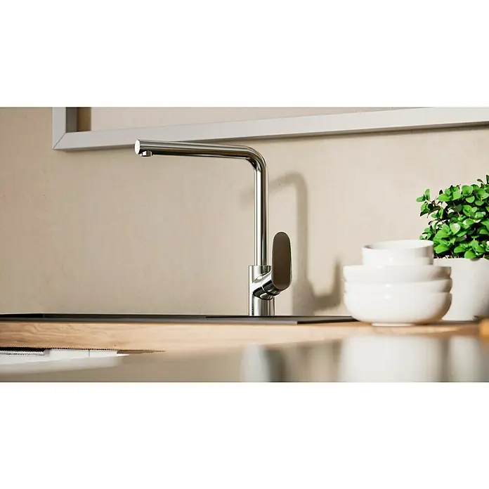Hansgrohe Grifo de cocina Focus M41 - Caño en L, Cromo, Brillante - Primer plano de un moderno grifo de cocina cromado, elegante y funcional, sobre un fondo neutro con cuencos blancos y una planta.