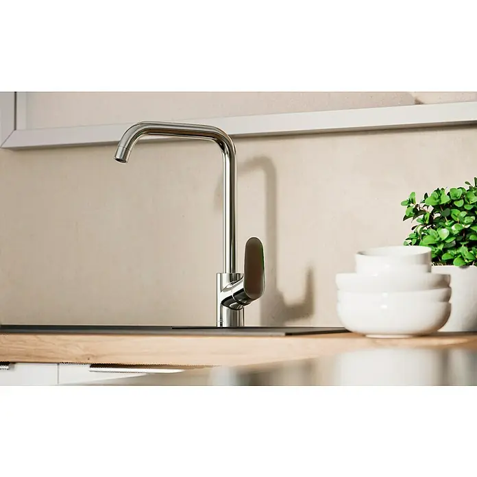 Hansgrohe Grifo de cocina Focus M41 - Caño en U, Cromo, Brillante - Un elegante grifo de cocina cromado es el centro de atención, complementado con cuencos blancos y una planta verde para un ambiente moderno.