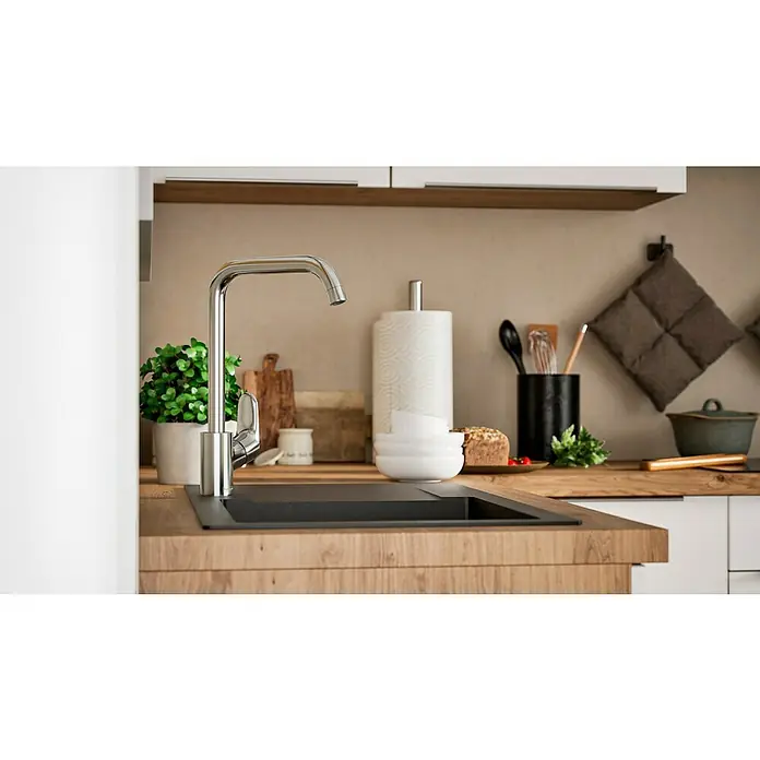 Hansgrohe Grifo de cocina Focus M41 - Caño en U, Cromo, Brillante - Primer plano de un fregadero de cocina moderno con un elegante grifo, rodeado de utensilios de cocina y decoraciones sobre una encimera de madera.