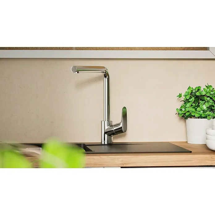Hansgrohe Grifo de cocina Focus M41 - Caño en L, Cromo, Brillante - Elegante grifo de cocina cromado junto a un fregadero y una planta verde en maceta, añadiendo estilo y funcionalidad.