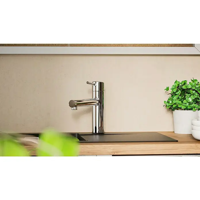 Grohe Concetto Spültischarmatur - Chrom, Glänzend, Ausziehbar - Nahaufnahme einer glänzenden Küchenarmatur mit modernem Design auf einer Arbeitsplatte mit Spüle und Pflanze im Hintergrund.