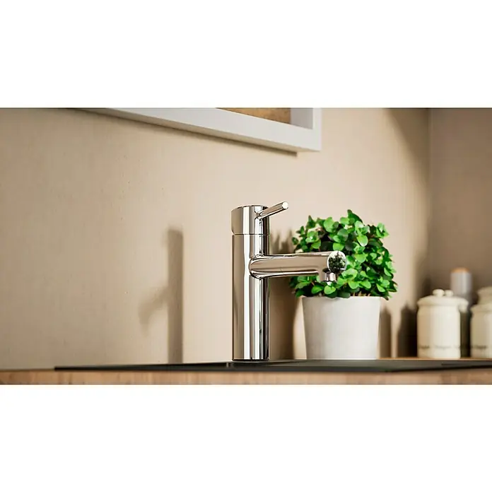 Grohe Concetto Spültischarmatur - Chrom, Glänzend, Ausziehbar - Nahaufnahme einer glänzenden Armatur mit rundem Auslauf, einem schlanken Hebel und einer Zimmerpflanze im Hintergrund, die für einen modernen Touch sorgt.