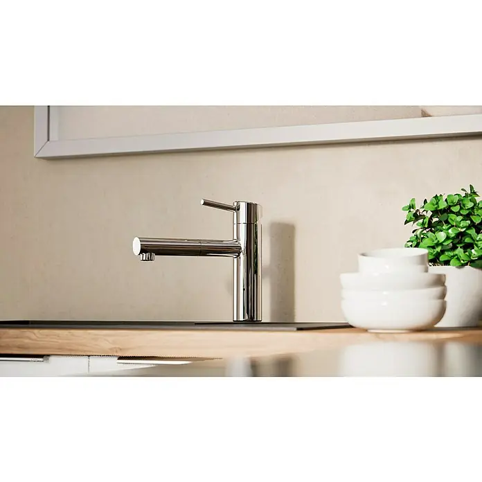 Grohe Concetto Spültischarmatur - Chrom, Glänzend, Ausziehbar - Elegante Chromarmatur vor beiger Wand mit Schüsselstapel und Topfpflanze. Die Armatur ist minimalistisch und modern gestaltet.