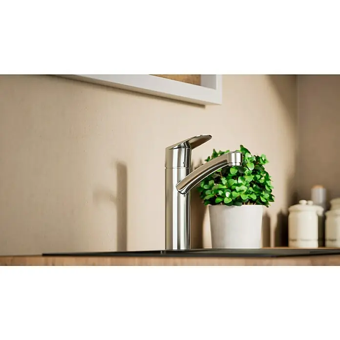 Hansgrohe Grifo de cocina - Cromo, Brillante - Elegante grifo de acero inoxidable sobre una encimera de cocina, con una planta verde en maceta que añade un toque moderno.