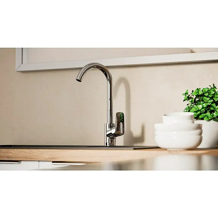 Hansgrohe Grifo de cocina Logis 260 - Cromo, Brillante - Primer plano de un grifo brillante sobre una encimera de cocina, junto a cuencos blancos y una maceta con plantas verdes, bajo un cuadro enmarcado.