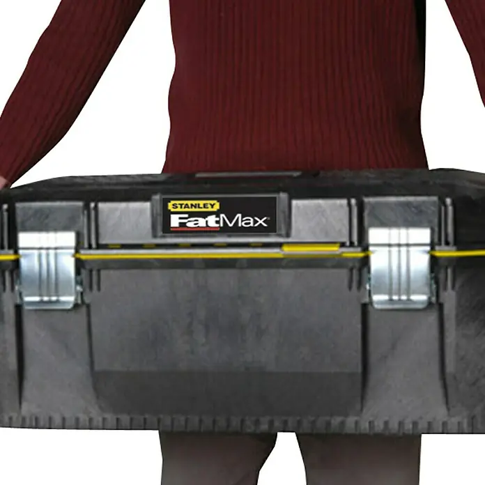 Stanley FatMax Caja para herramientas Structural - Tamaño: 28'', 71 x 28 x 30 cm, Protegido contra salpicaduras de agua - Una persona lleva una caja de herramientas Stanley FatMax. La caja es negra con detalles amarillos y cierres plateados.