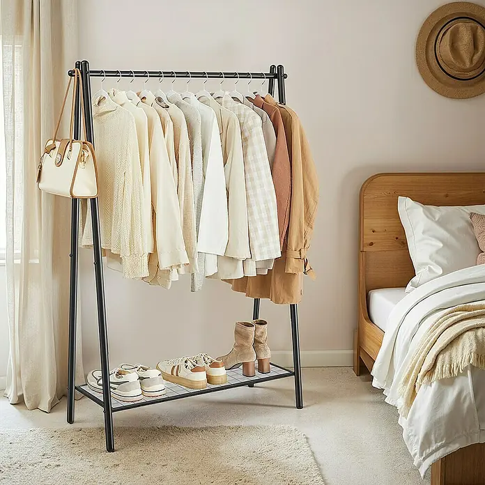 Garderobenständer - L x B x H: 33,5 x 92,5 x 153 cm, Schwarz - Bild einer Kleiderstange mit Ablage für Schuhe, behangen mit heller Kleidung und einer Handtasche, neben einem Bett und einem Teppich.