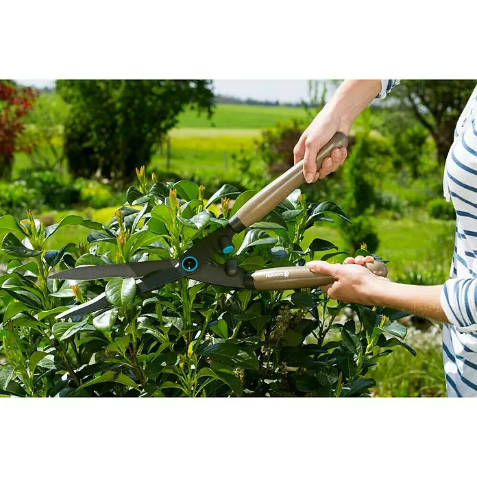 Gardena Hand-Heckenschere NatureCut - Länge: 580 mm - Eine Person benutzt eine Gardena Strauchschere, um einen grünen Strauch zu schneiden, wobei die Schere und die Handhabung im Fokus stehen.