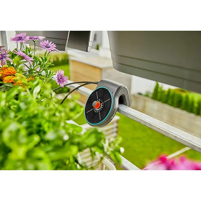 Gardena Bewässerungssteuerung AquaBloomSolarbetrieben - Nahaufnahme einer Gardena Micro-Drip-System Blumenkastenbewässerung, die an einem Balkongeländer befestigt ist und Pflanzen bewässert.