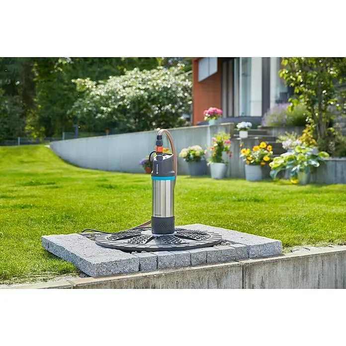 Gardena Drucktauchpumpe 6100/5 inox automatic - 1.100 W, Max. Fördermenge: 6.100 l/h - Gardena Tiefbrunnenpumpe mit Edelstahldesign auf einem quadratischen Steinsockel im Garten.