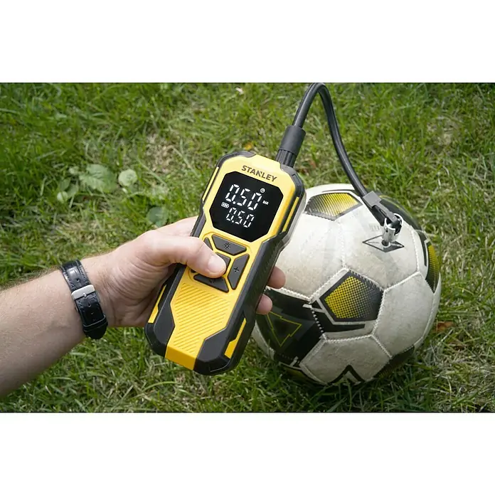 DeWalt Akku-Luftpumpe SXIF0101 - 11,1 V, 10 bar, Füllleistung: 14,2 l/min - Ein Mann pumpt einen Fußball mit einem gelben STANLEY Luftkompressor auf, der 0,50 bar Druck anzeigt.